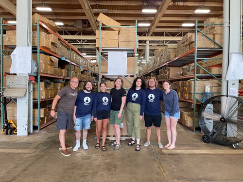 Heidi Baumgart stands with her summer interns in a warhorse filled with cardboard boxes.